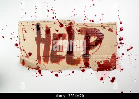 A desperate message with the word HELP written in blood on a piece of torn cardboard, surrounded by splatters. Ideal for horror, crime, and emergency Stock Photo
