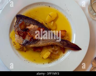 Delicious grilled gilthead bream with side dish of stewed potato slices in vegetable sauce.. Stock Photo