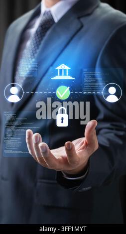 Businessman displaying holographic icons of a bank, lock, and user connections, representing secure online transactions and cybersecurity Stock Photo