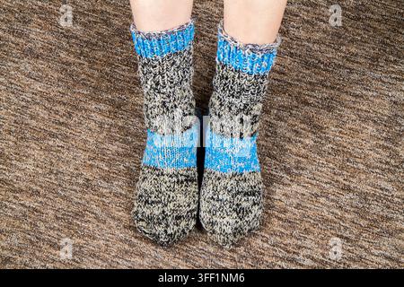 A pair of homemade knitted socks on women's feet. Warm wool socks Stock Photo
