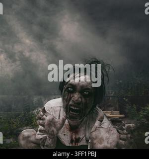 A frightening, blood-stained male zombie with white eyes screams and reaches out under a dark, stormy sky. Concept of Halloween Stock Photo