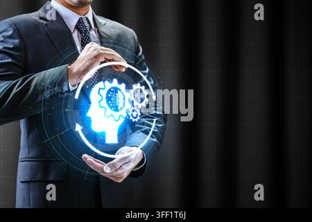 Hologram of a human head with gears in a business hand, symbolizing artificial intelligence, deep learning, and cognitive computing. AI Education conc Stock Photo