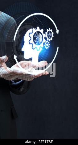 Hologram of a human head with gears in a business hand, symbolizing artificial intelligence, deep learning, and cognitive computing. AI Education conc Stock Photo