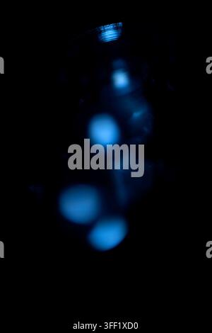 Minimalist abstract image featuring three vertical blue and white bokeh light circles against a solid black background. Abstract blue background Stock Photo