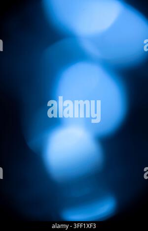 Abstract background featuring soft, out-of-focus glowing blue bokeh lights on a dark backdrop. Abstract blue background Stock Photo