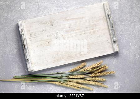 Empty white wooden tray, board with handles and dry ears of corn on gray stone table top view Stock Photo