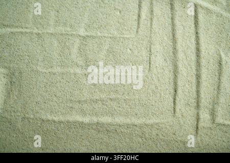 A top-down close-up shot of fine beige sand showing subtle raked geometric patterns and lines, creating a calm, minimalist textured background. Summer Stock Photo