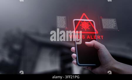 Hand holding a smartphone displaying a red holographic virus alert warning with cyber security notification. Concept of Technology Security Stock Photo