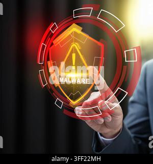 Businessman touching a virtual shield displaying a malware warning, representing cybersecurity threats and data protection. Cybersecurity concept Stock Photo