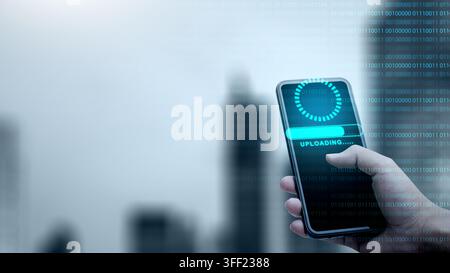 Hand holding a smartphone displaying an uploading progress bar with blue light overlays and binary code. Concept of cloud computing storage and digita Stock Photo