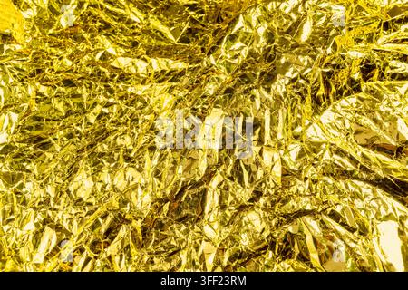 Crumpled gold foil texture background with shiny metallic wrinkles and reflective creases. Holiday, celebration or texture background Stock Photo