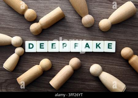 Deepfake word on tiles surrounded by wooden figures symbolizing people and manipulation Stock Photo