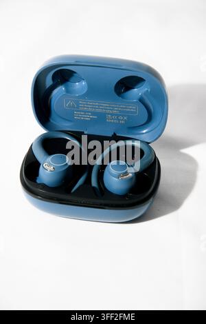 Pair of blue true wireless sports earbuds with open charging case on a white background Stock Photo