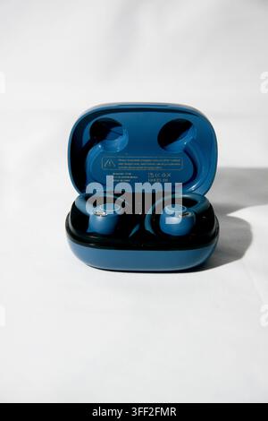 Pair of blue true wireless sports earbuds with open charging case on a white background Stock Photo