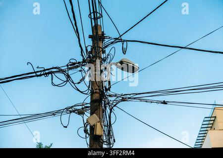 A utility pole covered with tangled overhead cables and a streetlight stands in Belgrade. The image suits telecom, electricity, infrastructure and Stock Photo