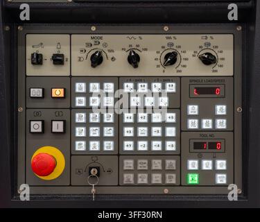 Industrial CNC machine control panel keyboard with emergency stop button, spindle controls, digital displays and illuminated function keys Stock Photo