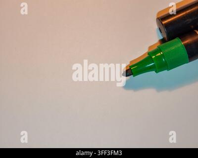 Green marker pen with its cap resting on top, positioned in the upper right corner, showing the felt tip on a checkered transparent background with am Stock Photo