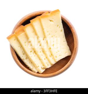 Slices of smoked semi-hard cheese, stacked in a wooden bowl. Cross-sections from Traunstein smoked cheese from Austria. Photo Stock Photo