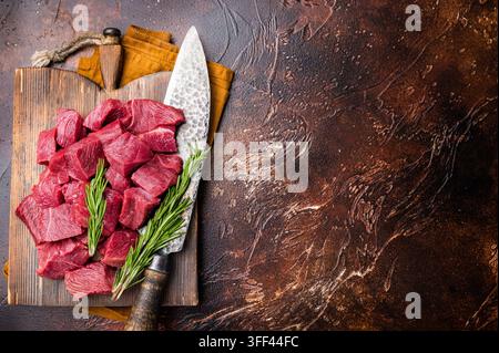 Diced Raw Venison meat, fresh Wild Roe Deer Game Meat on butcher cutting board. brown background. top view Stock Photo