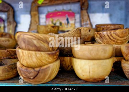 Neat stacks of unique handcrafted olive wood bowls displaying rich organic grain patterns on a rustic blue shelf at a market bazaar in Kairouan, Tunis Stock Photo