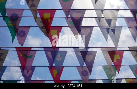 Colorful triangular bunting flags hanging against the sky as festive outdoor street decoration. Stock Photo