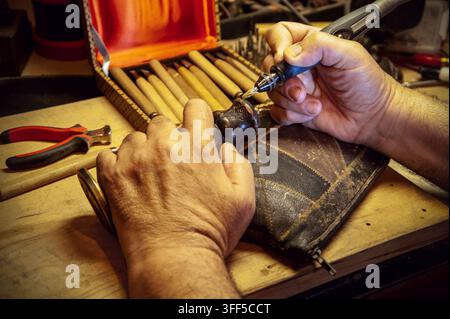 Close up of craftsman hands. Craftsman engraves wooden handle for brass stamp. Stock Photo