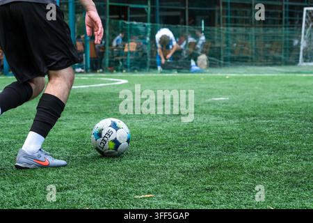 Kyiv, Ukraine – September 05, 2026: Low angle view of a futsal player approaching a soccer ball on an artificial turf pitch during a local tournament Stock Photo