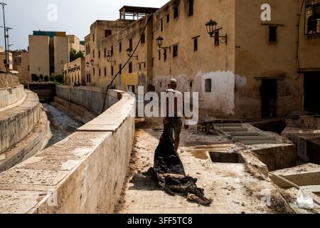 A man works on a construction site next to a narrow canal in an old city with yellow buildings. Stock Photo