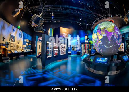 Faces of Our Planet Exhibit in Washington DC | WASHINGTON D.C., United States — Portraits under the banner "Faces of Our Planet" hang beside a rotating globe in the National Air and Space Museum's "One World Connected" gallery. The images pair remote communities from Uganda to the Pacific Islands with the satellite technology overhead, illustrating how orbiting hardware built for Cold War reconnaissance now links even the most isolated populations to global networks. Stock Photo