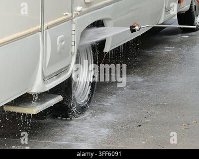 Close-up of RV side and wheel being cleaned with strong pressure washer spray Stock Photo