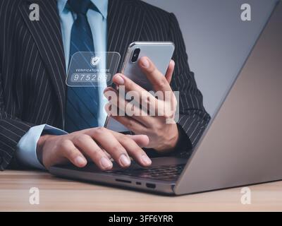 Businessman in suit using smartphone and laptop with verification code interface. Secure login, identity verification, multi-factor authentication, en Stock Photo