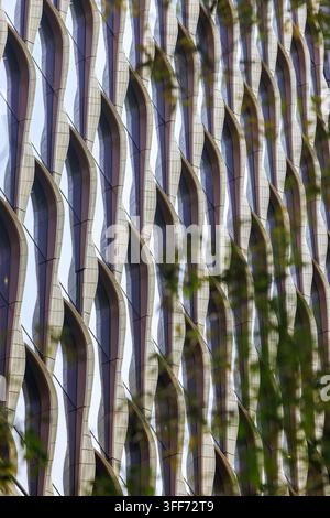 Unique exterior building facade, featuring a distinct repeating pattern of crystalline, sail-like fins creating a textured, undulating diamond grid. Stock Photo