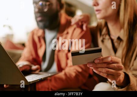 Close up of diverse couple, African American man and Caucasian woman shopping online with laptop and credit card. Image suitable for Black Friday sale Stock Photo