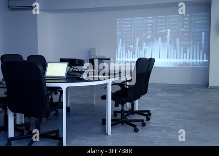 Interior of data scientists office with workplace, laptops and diagrams projection on wall Stock Photo