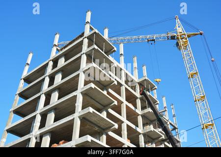 Building cranes on construction site with builders. Building high rise.Crane Construction. Tower Crane and Building Constructors on Construction Site. Stock Photo