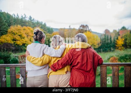 Rear view of three senior women on patio, looking at fall autumn. Stock Photo