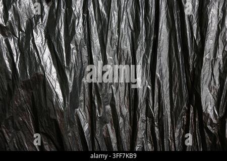 A black plastic texture wrinkle pattern crumpled vertical dark background abstract crumpled black plastic texture with vertical wrinkle pattern creati Stock Photo