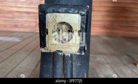 Weathered Electrical Outlet with Exposed Wiring on Dark Wall Stock Photo
