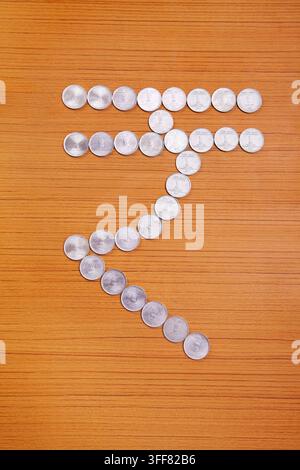New Indian rupee currency symbol created by arranging coins over wooden background Stock Photo