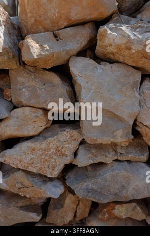 Bad Herrenalb Closeup view of beige limestone rocks with granular rough texture stacked into rustic stone wall, showing mineral veins, cracked edges, Stock Photo