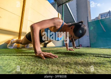 Athletic woman doing push ups during outdoor workout Stock Photo
