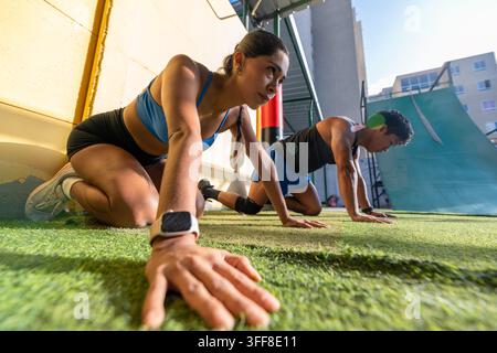 Determined couple doing exercises on turf Stock Photo