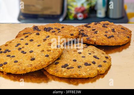 Close-up view of several large, freshly baked oatmeal chocolate chip cookies with dark chocolate pieces scattered across their surface, displayed on a Stock Photo