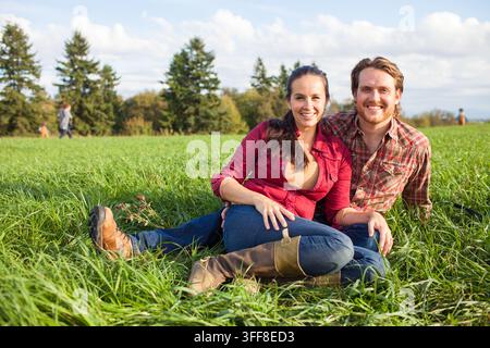 Happy couple relaxing together in a grassy field Stock Photo