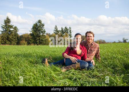 Smiling couple sitting together in a grassy field Stock Photo