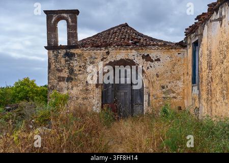Weathered facade and stone belfry of an abandoned historic chapel overgrown with dry weeds in Anaga Tenerife Stock Photo
