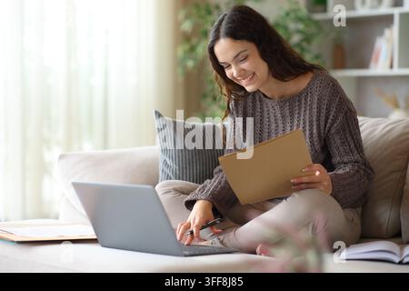 Happy telecommuter checking documents working online sitting on a couch at home Stock Photo