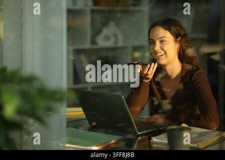 Happy telecommuter using ai to work online at home viewed through a window Stock Photo
