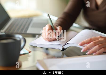 Close up portrait of an office worker hands working writing in paper agenda Stock Photo
