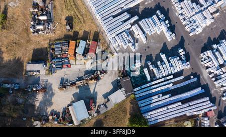 Aerial view of a construction material storage facility with rows of stacked white bags, industrial equipment, and containers in Milan, Lombardy, Ital Stock Photo